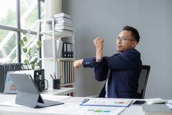 Young businessman is taking a break from work to stretch his arms at his desk